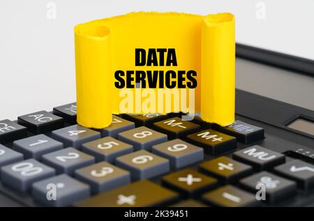 Business concept. On the calculator is a yellow, twisted paper plate with the inscription - DATA SERVICES Stock Photo