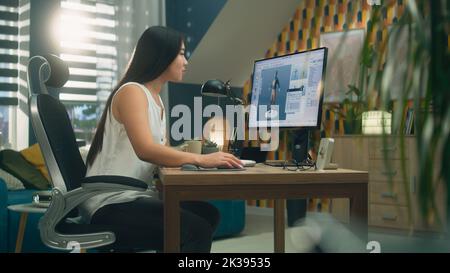 Asian 3D designer creating 3D model of style and design of clothes in professional program on personal computer while working remotely at home Stock Photo