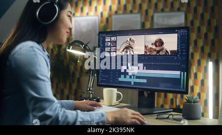 Asian woman in headset editing video with astronauts for client in program on personal computer while working at the table from home office. Freelance Stock Photo