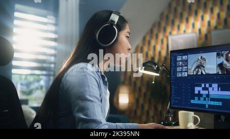 Asian woman in headset editing video with astronauts for client in program on personal computer while working at the table from home office. Freelance Stock Photo