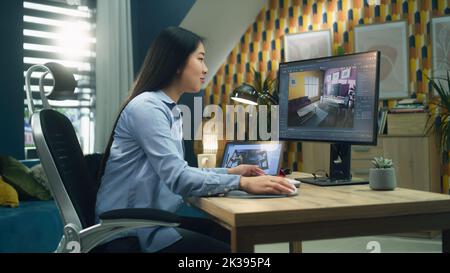 Female asian designer working remotely from home office and making 3D visualization of house interior in computer program using pc and digital tablet Stock Photo