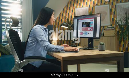 Female asian web designer using personal computer for creating website in professional constructor while working on project remotely at home. Freelance Stock Photo