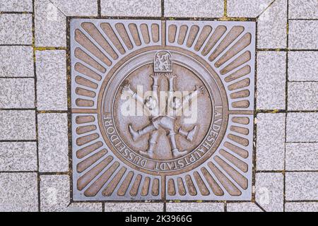21 July 2022, Dusseldorf, Germany: Sewer lid or manhole with emblem or coat of arms of Dusseldorf at city street