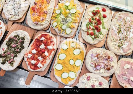 Variety of raw pizzas to bake. Restaurant. Pizzeria. Italian food. Stock Photo