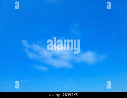 Single wispy cloud in a bright blue sky Stock Photo
