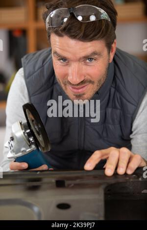 workman using an angle grinder on a car door Stock Photo