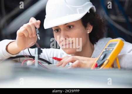 female electrician testing charge to spotlight Stock Photo