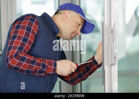 worker man installs windows with screwdriver Stock Photo