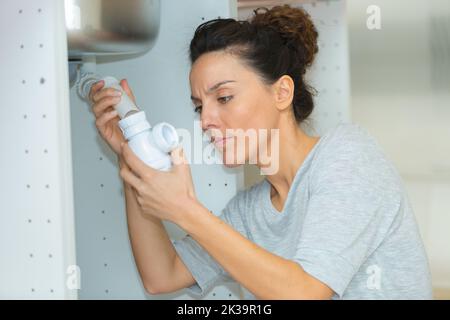 woman tightening pipe under sink with worktool at home Stock Photo