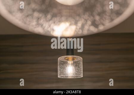 Hanging incandescent light bulb with tungsten filaments with a wall background. Stock Photo