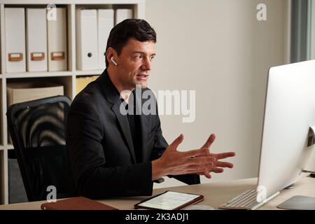 Entrepreneur having online meeting with colleagues and discussing project details Stock Photo