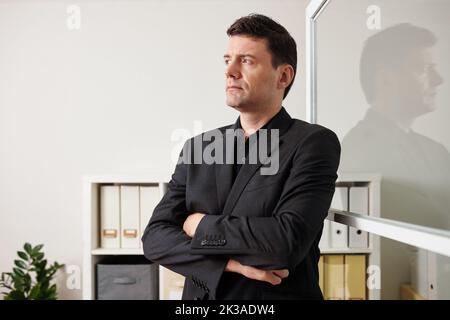 Portrait of frowning pensive businessman crossing arms and looking away Stock Photo