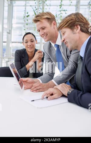Weve made some great progress in this department. A young businessman showing his colleagues something on a digital tablet. Stock Photo