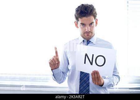 Saying NO to unethical behavior in business. Portrait of a serious-looking businessman holding a sign that says NO. Stock Photo