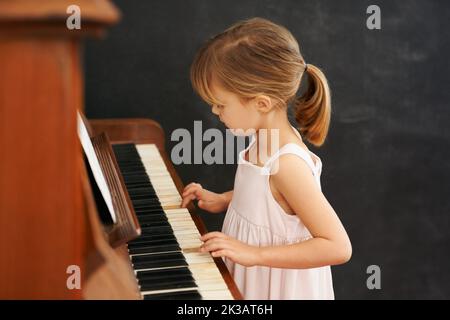 Practising for the recital. a little girl playing the piano. Stock Photo