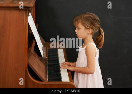 Practising for the recital. a little girl playing the piano. Stock Photo