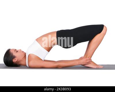 Building a strong back and core. A young woman doing stretches while isolated on white. Stock Photo