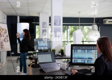 Architect working in 3d modeling software, multi store building model on computer screen. Architecture office employee working in coworking space, real estate agency tools, plan drafts. Stock Photo