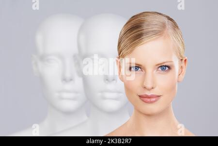 Dont be another face in the crowd. A beautiful young woman standing amongst a row of mannequins. Stock Photo