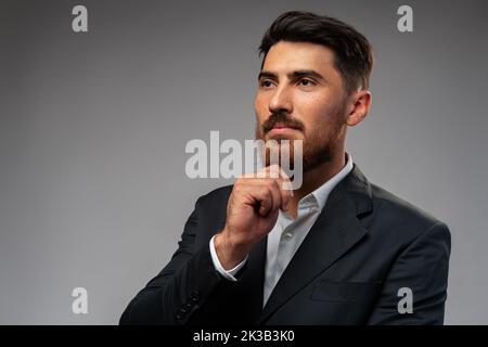 Studuo shot of thinking businessman standing over gray background Stock Photo