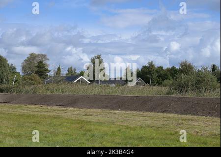 an earth embankment in front of the houses as protection against flooding of the sea, Høll, Denmark, September 18, 2022 Stock Photo