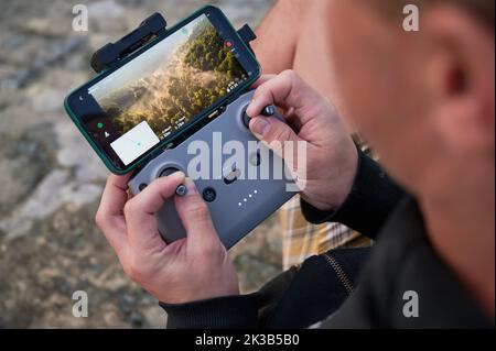 Close up man operating drone using remote controller. Man using drone at sunset for photos and video making Stock Photo