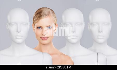 Dont be another face in the crowd. A beautiful young woman standing amongst a row of mannequins. Stock Photo