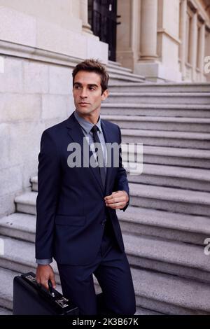 Corporate confidence. A handsome businessman standing with his briefcase on the steps of a city building. Stock Photo