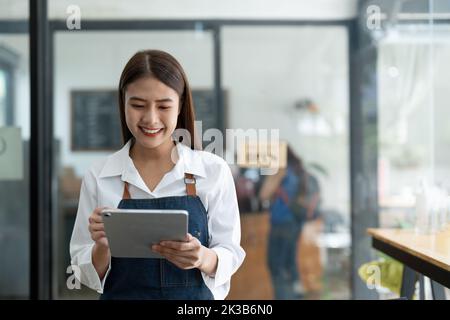 Asian women Barista smiling working small business owner using tablet ordoring food and drink cafe concept Stock Photo