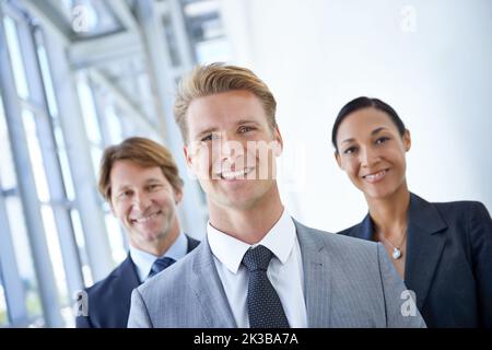 Heading towards a bright future starts with your attitude. Three smiling businesspeople standing together. Stock Photo