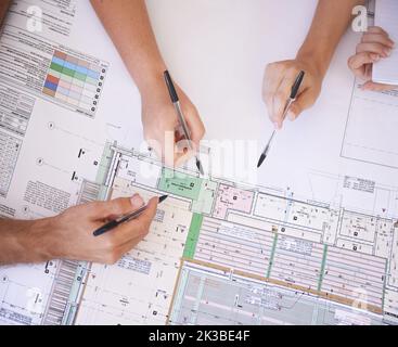 Planning out the fine details. Aerial view of a group of architects working on an architectural plan. Stock Photo