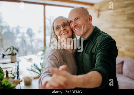 Senior couple in love dancing together in their modern living room. Stock Photo