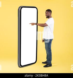 African guy using big phone touching blank screen in studio Stock Photo