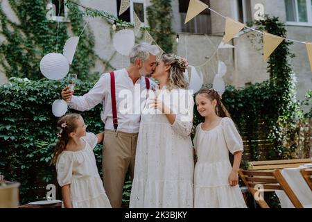 Mature bride and groom toasting with their daughters at wedding reception outside in the backyard. Stock Photo