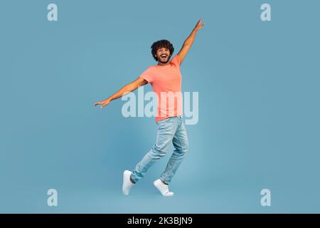 Positive hindu guy fooling over blue studio background Stock Photo