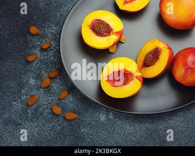 fresh sweet peaches and almond nuts on dark table. Fresh organic fruit Flat lay on old rustic background. Top view copy space Stock Photo