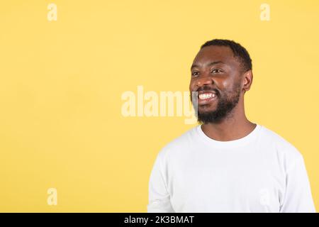 Happy Black Guy Looking Aside At Free Space, Yellow Background Stock Photo