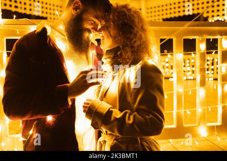 Two young people hugging and loving each other under Christmas lights Stock Photo