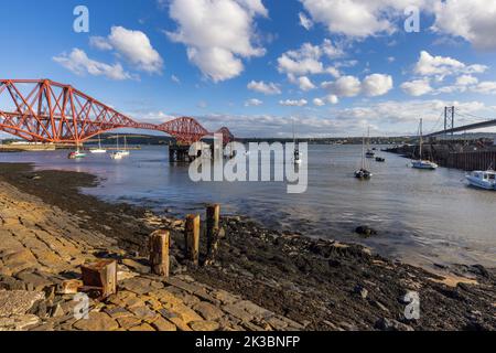 Low tide at North Queensferry Harbour, with the mighty Forth bridges spreading across the Firth of Forth connecting north and south Queensferry. Stock Photo