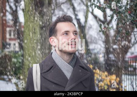 Portrait of young handsome man with beard smiling in winter snow Stock Photo