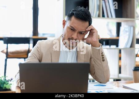 Tired and worried business man holding his head on hand at his workplace in the office Stock Photo