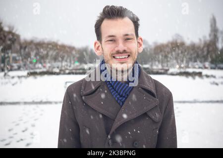 Portrait of young handsome man with beard smiling laughing looking at camera in winter snow Stock Photo