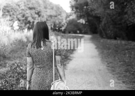 Grayscale photo of a woman walking by a path through the forest Stock Photo