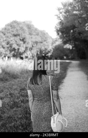 Grayscale photo of a woman walking by a path through the forest Stock Photo