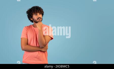 Pensive indian guy looking at copy space over blue background Stock Photo