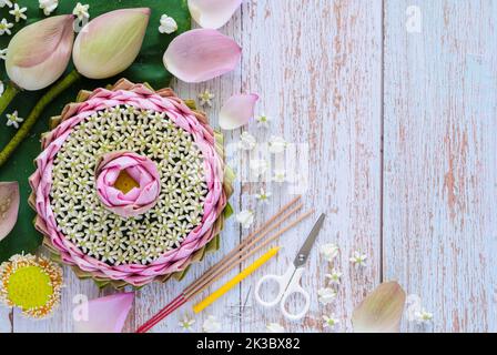 Pink lotus petal krathong for Thailand Loy Krathong festival making from lotus and crown flower with incense stick and candle on wooden background. Stock Photo