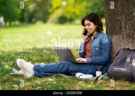 Freelance Work For Students. Arab Female Using Laptop And Cellphone In Park Stock Photo