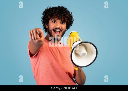 Handsome eastern guy shouting through loudspeaker and gesturing Stock Photo