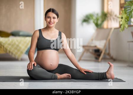 Fitness During Pregnancy. Beautiful Young Pregnant Woman In Activewear Posing At Home Stock Photo