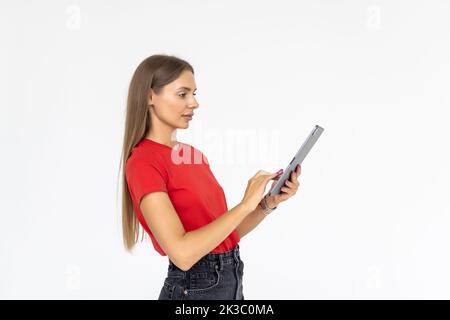 Happy girl in white shirt using tablet. Smiling woman with tablet pc, isolated on grey background Stock Photo